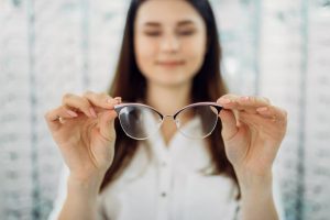 Accent Eye Care female-customer-holds-glasses-in-hand-optic-store-8YUFT9K  